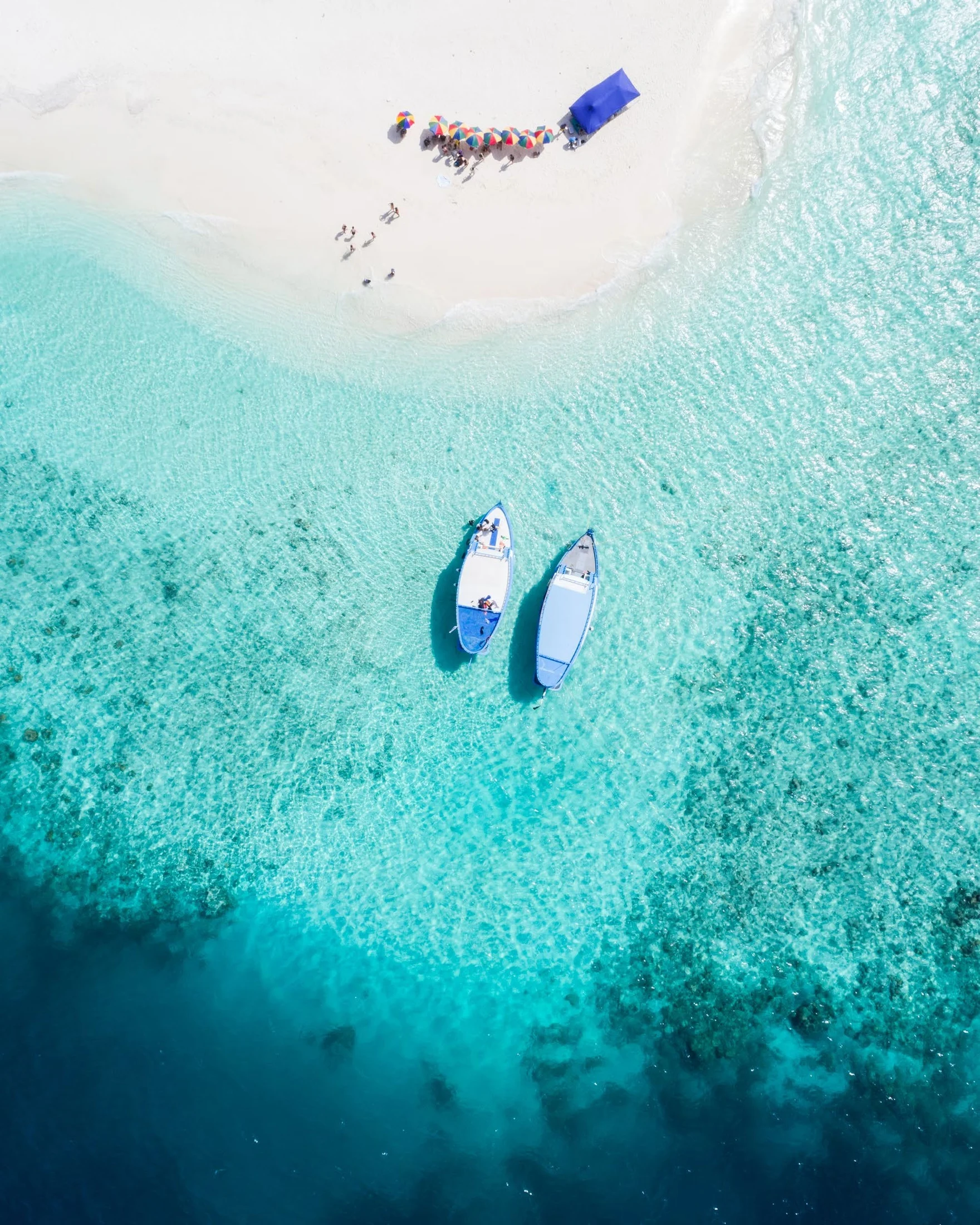 Clear turquoise water, boats, and white sand from the EVA Bay brochure